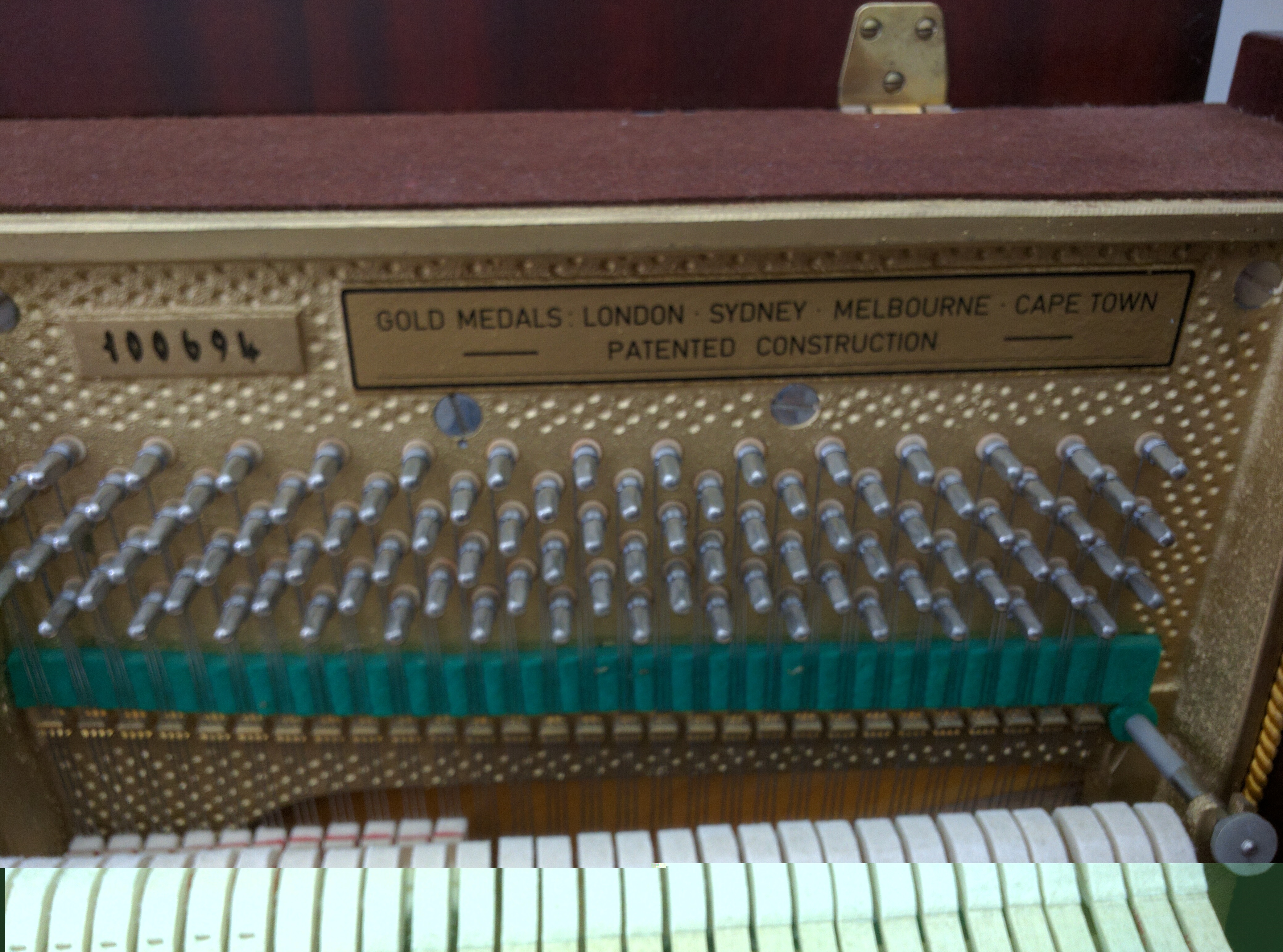 close up of serial number, tuning pins, and info plate on Scholze Upright Piano
